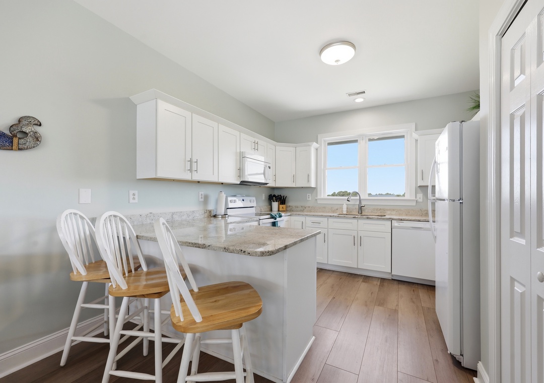 You'll love preparing meals in this bright, fully equipped kitchen with granite countertops, modern appliances, and a convenient breakfast bar for casual dining.