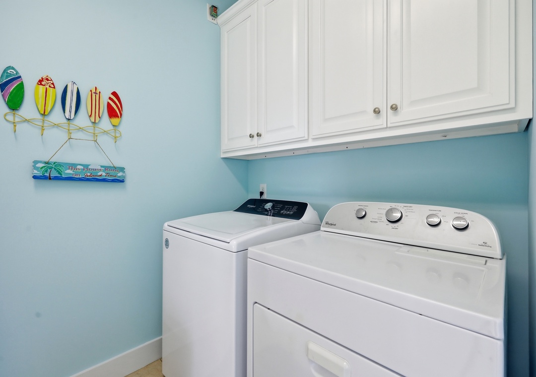 Keep your wardrobe fresh with your own in-unit washer and dryer. White cabinets provide convenient storage in this cheerful laundry space with coastal-inspired decor.