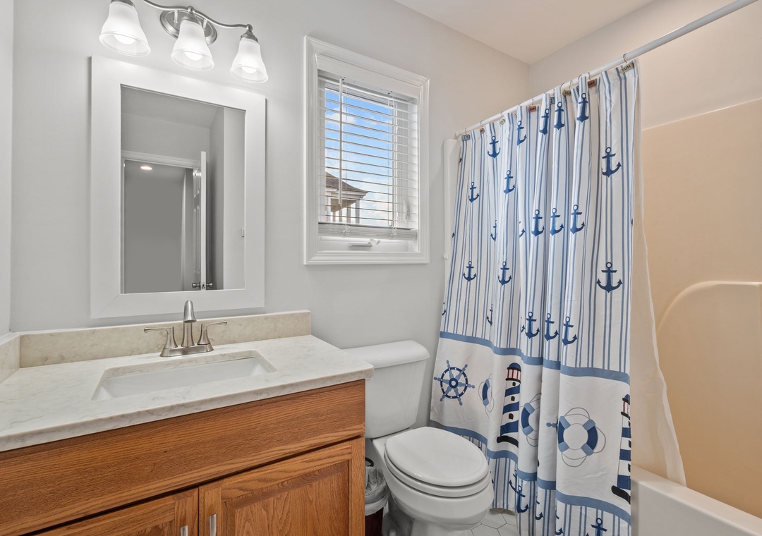 Refresh in your charming nautical bathroom featuring coastal-themed touches and bright natural light from the window.