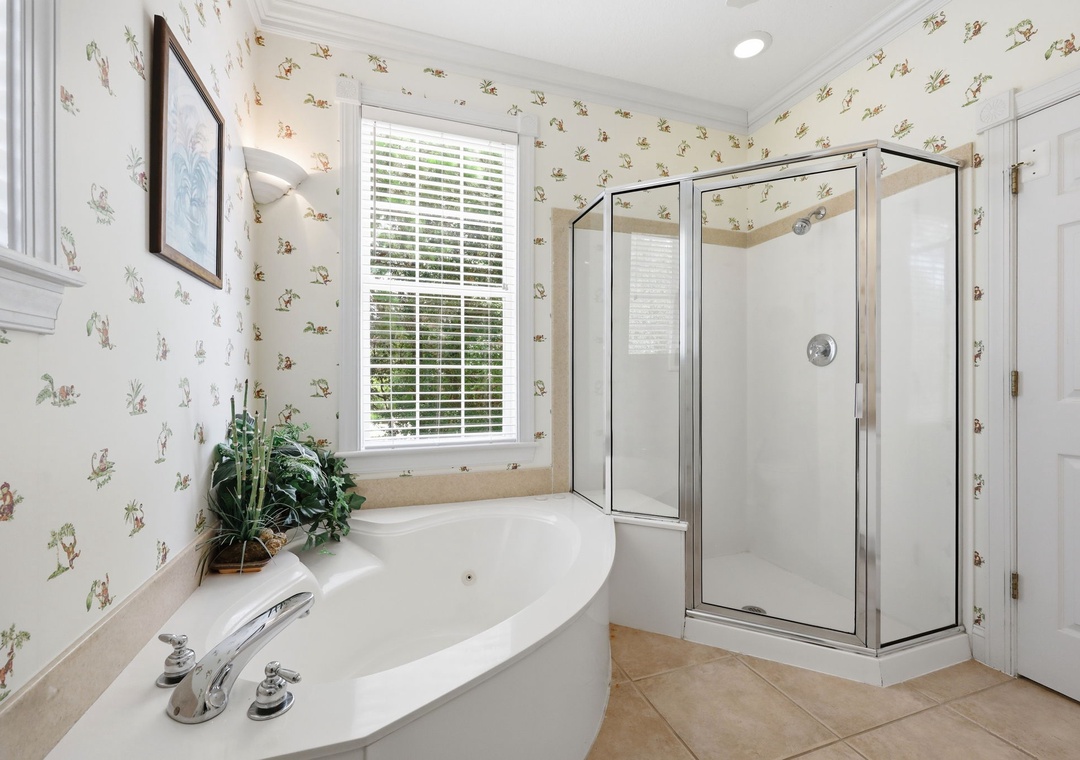 Unwind in your private bathroom retreat with a soaking tub and separate glass shower—charming floral wallpaper adds a cozy, cottage-inspired touch.