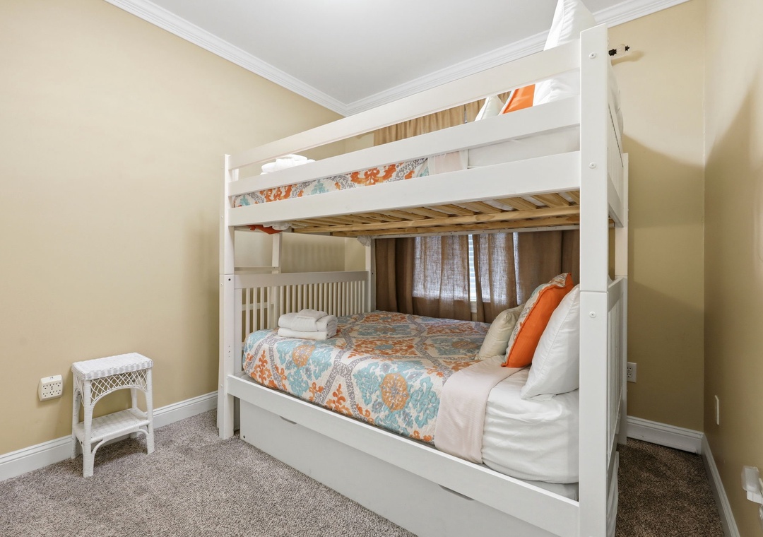 This cozy bedroom features a charming white bunk bed dressed in cheerful linens, perfect for kids or extra guests. You'll appreciate the neutral tones and soft carpet underfoot, creating a warm and inviting retreat.