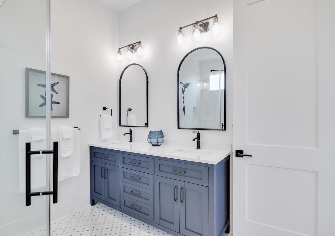 Refresh in your private bathroom featuring dual vanities, elegant arch mirrors, and modern fixtures that blend style with comfort.