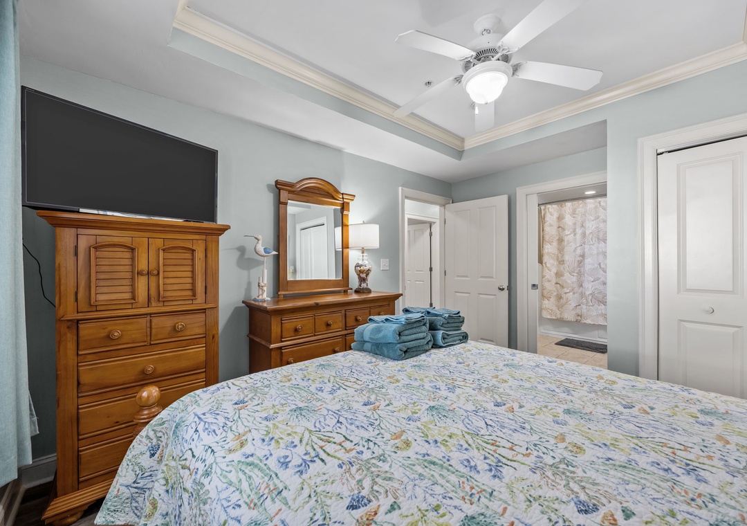 Your restful bedroom features elegant wooden furniture, a wall-mounted TV, and fresh towels waiting for your arrival.