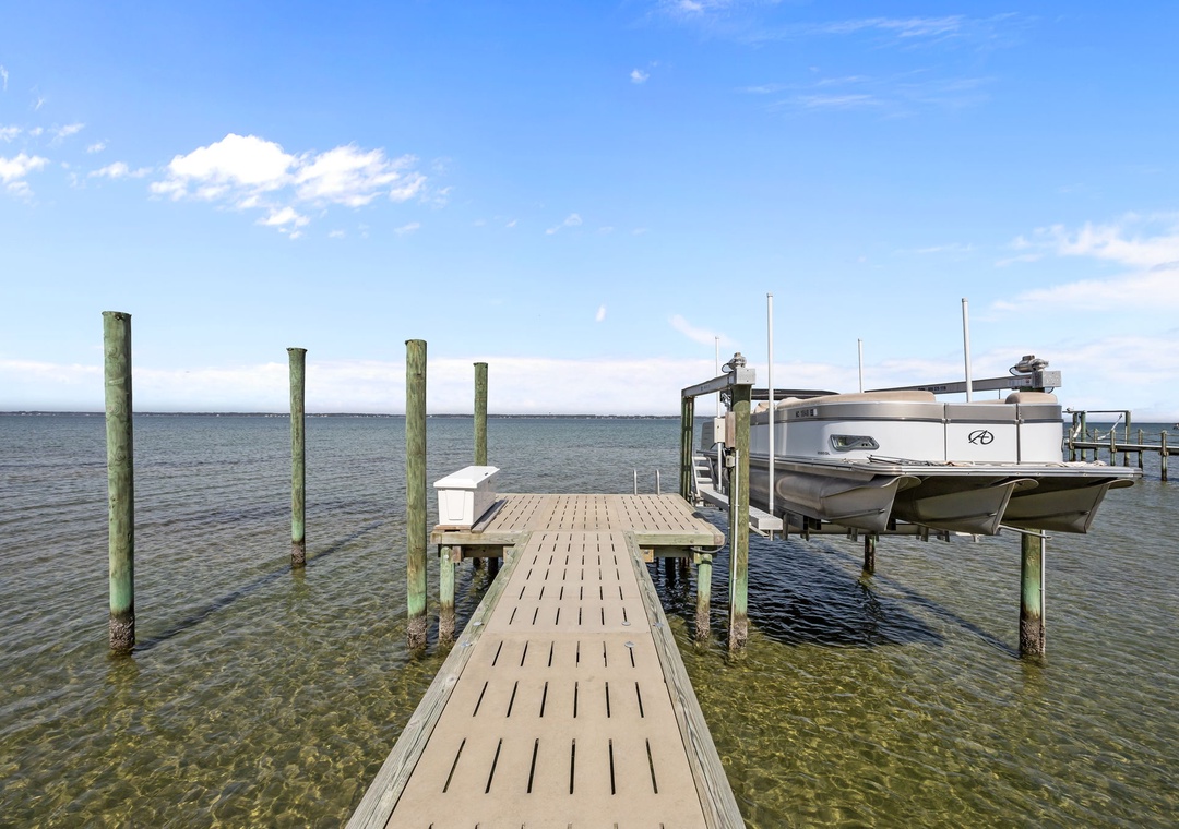 Private dock with boat access on crystal-clear waters under bright blue skies.