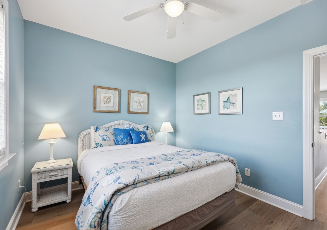 Drift off in your serene coastal-inspired bedroom, where calming blue walls and ocean-themed artwork create a peaceful retreat after a day of exploration.