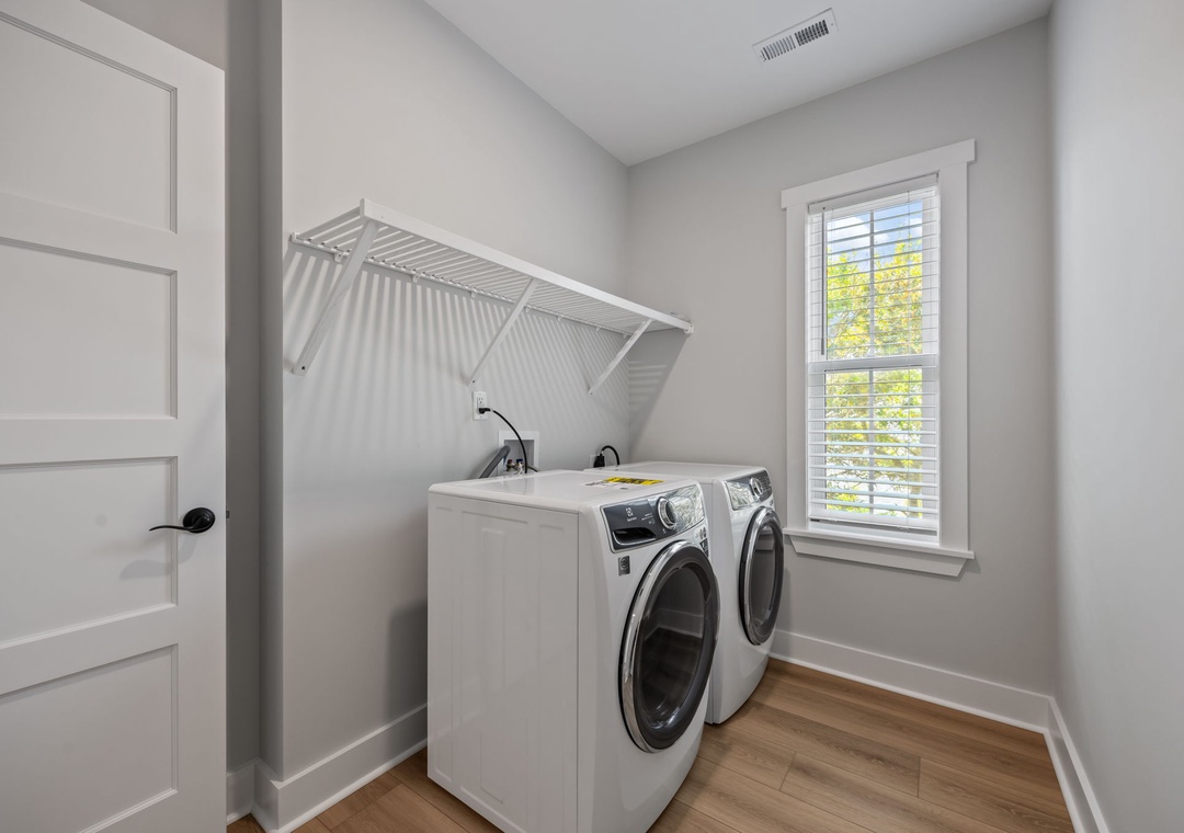 Keep your clothes fresh and clean in this bright, well-organized laundry room with modern machines and convenient hanging space.
