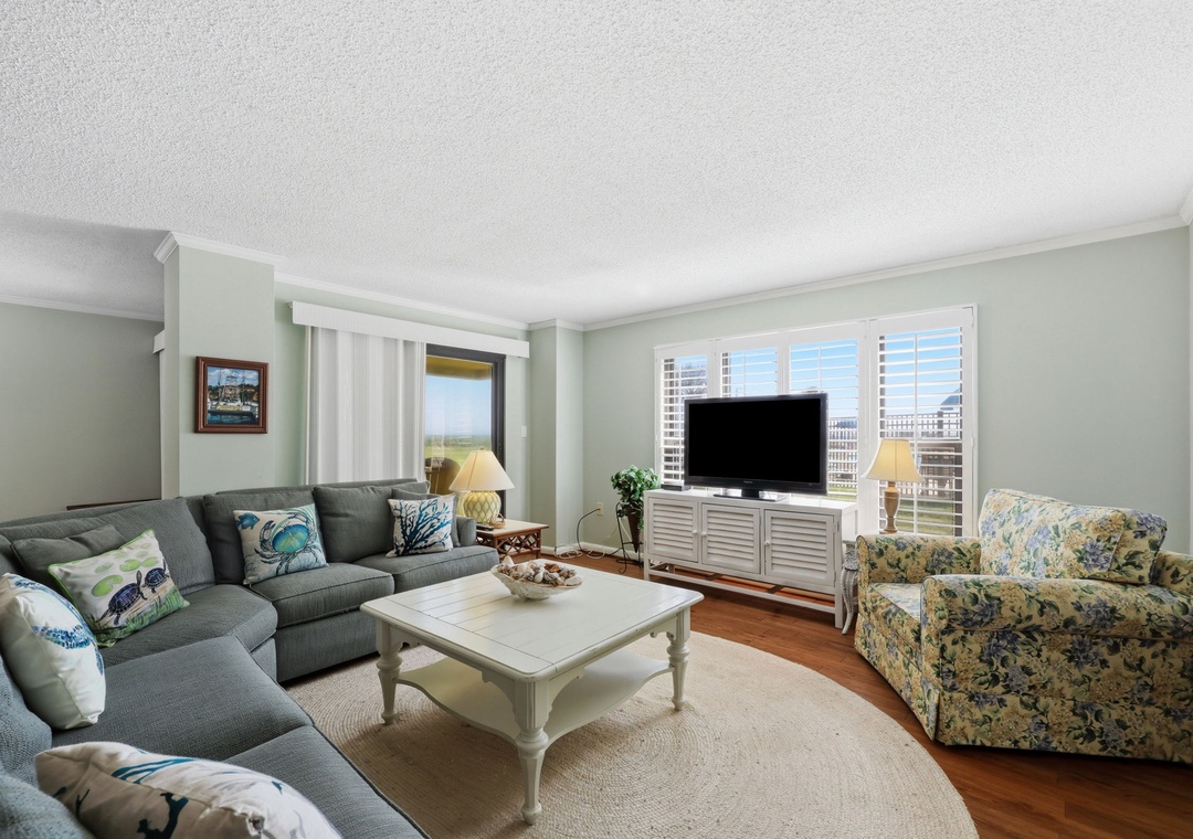Sink into plush seating and unwind as natural light pours through plantation shutters. Your coastal getaway features cozy furnishings, a large TV for movie nights, and serene views.