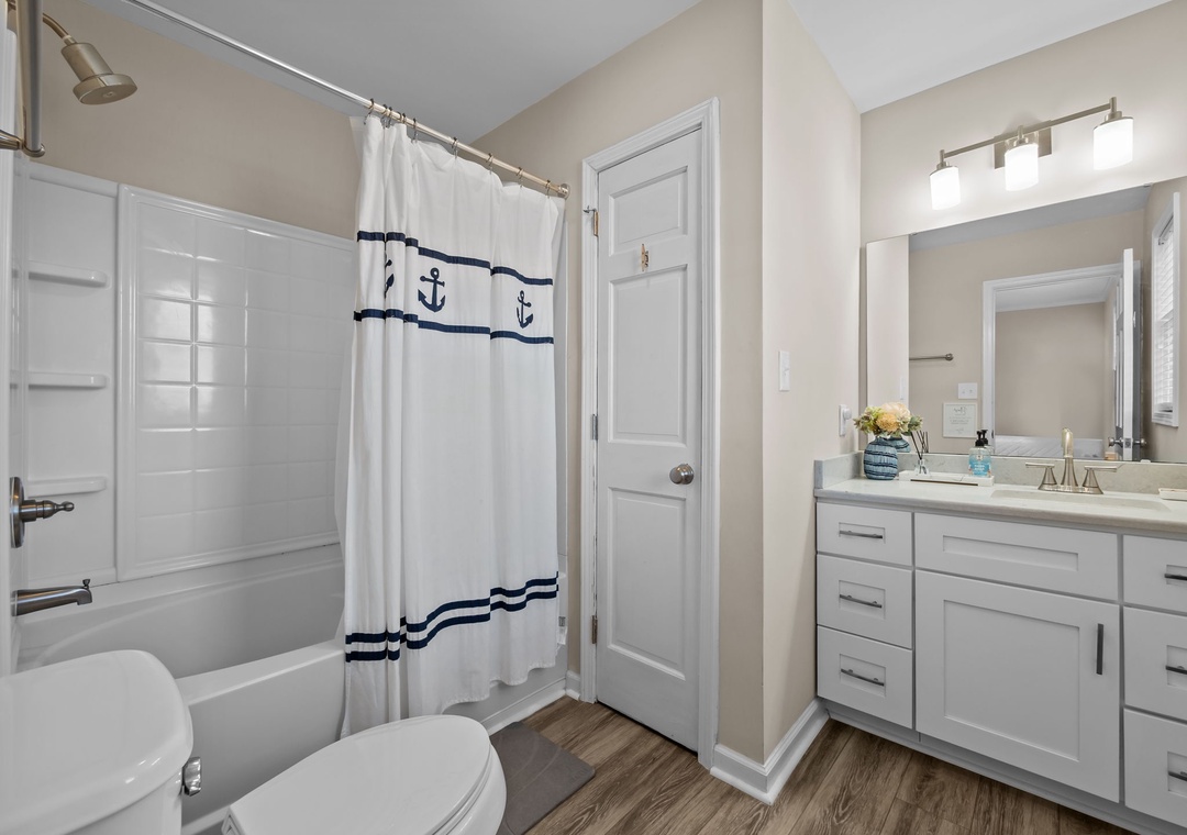 Refresh in your private bathroom featuring a spacious shower-tub combo and crisp nautical touches that bring coastal charm to your daily routine.