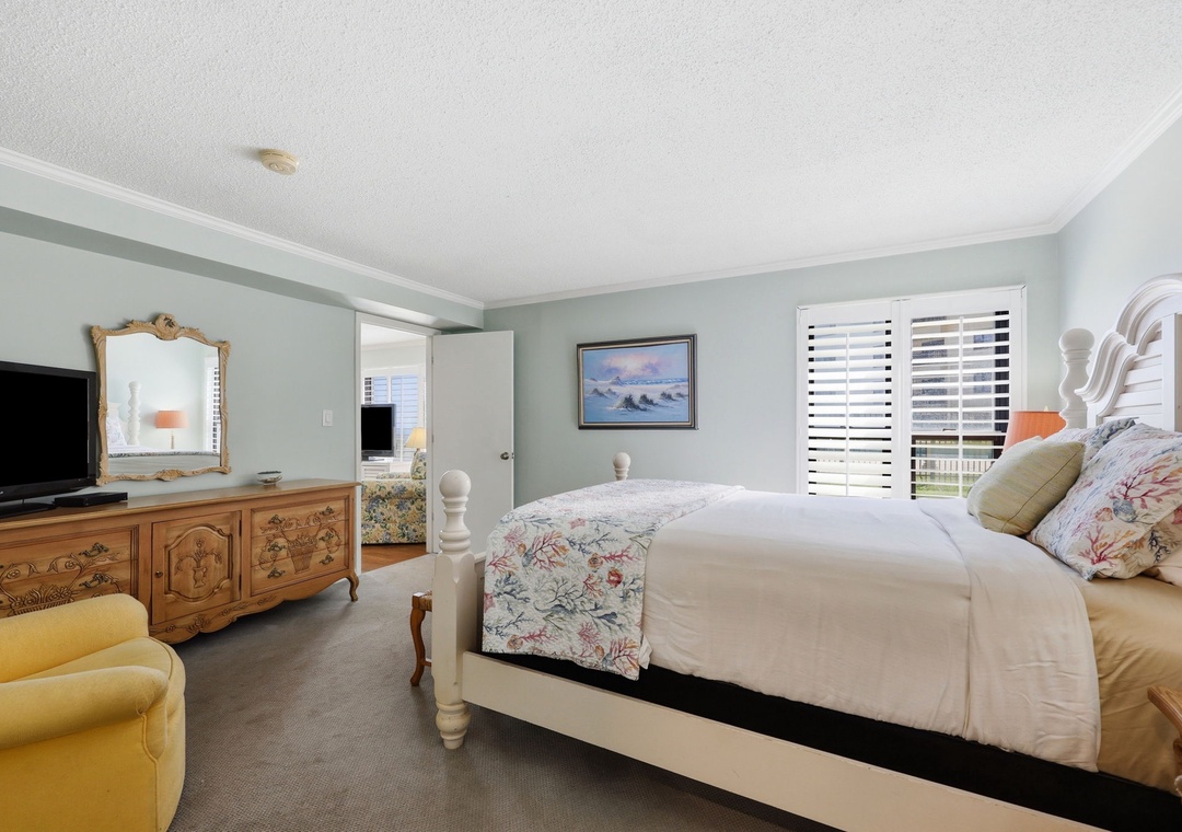 Picture yourself sinking into this plush bed after a day exploring, surrounded by soft coastal blues and charming vintage touches. Morning light filters through plantation shutters, inviting you to rest.