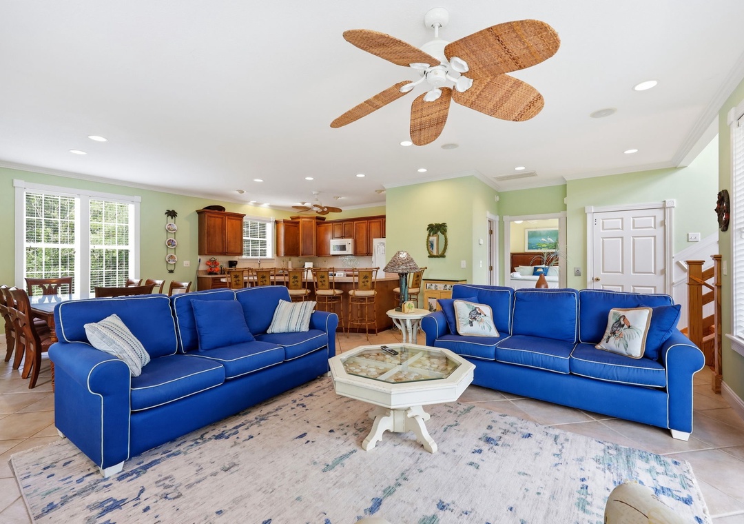 Bright coastal living awaits you in this spacious open-plan area with cheerful blue sofas, elegant dining space, and fully-equipped kitchen—perfect for gathering with loved ones.