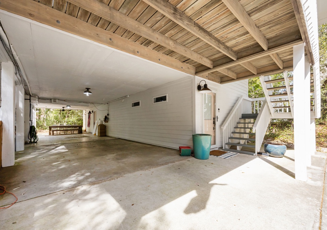 Spacious covered parking area provides convenient shelter for your vehicles with exposed beam ceiling and nearby staircase access.