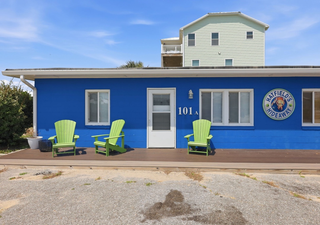 Charming blue beachside property with bright green seating on the deck welcomes guests to their coastal retreat at 101A Bluefields Hideaway.