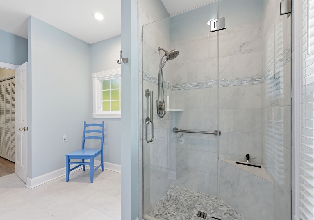 Refresh in your spacious walk-in shower with marble tile and rainfall showerhead—designed with accessibility features and coastal-inspired finishes for your comfort.