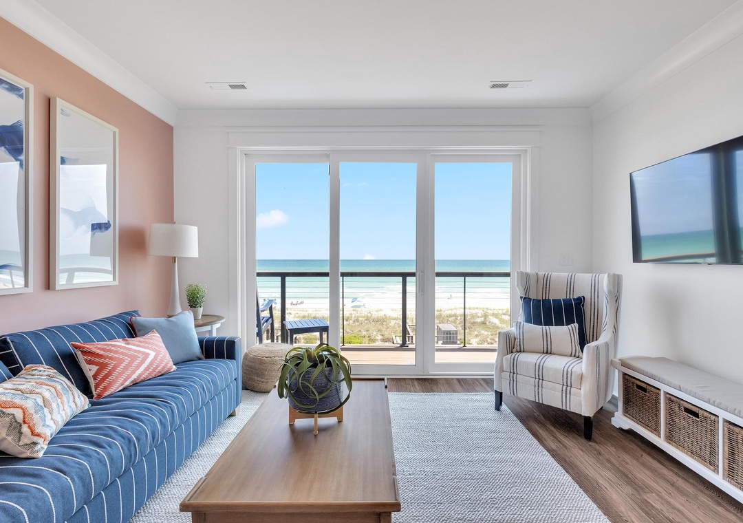 Sink into comfort in your bright living room, where the coastal palette and plush seating invite you to unwind. Glass doors open to your balcony, bringing the beach just steps away.