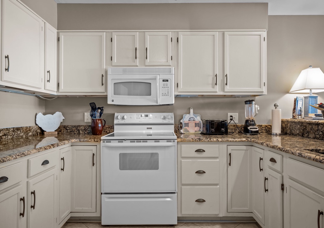 Your fully equipped kitchen awaits with granite counters, white appliances, and everything needed to create delicious meals during your stay.
