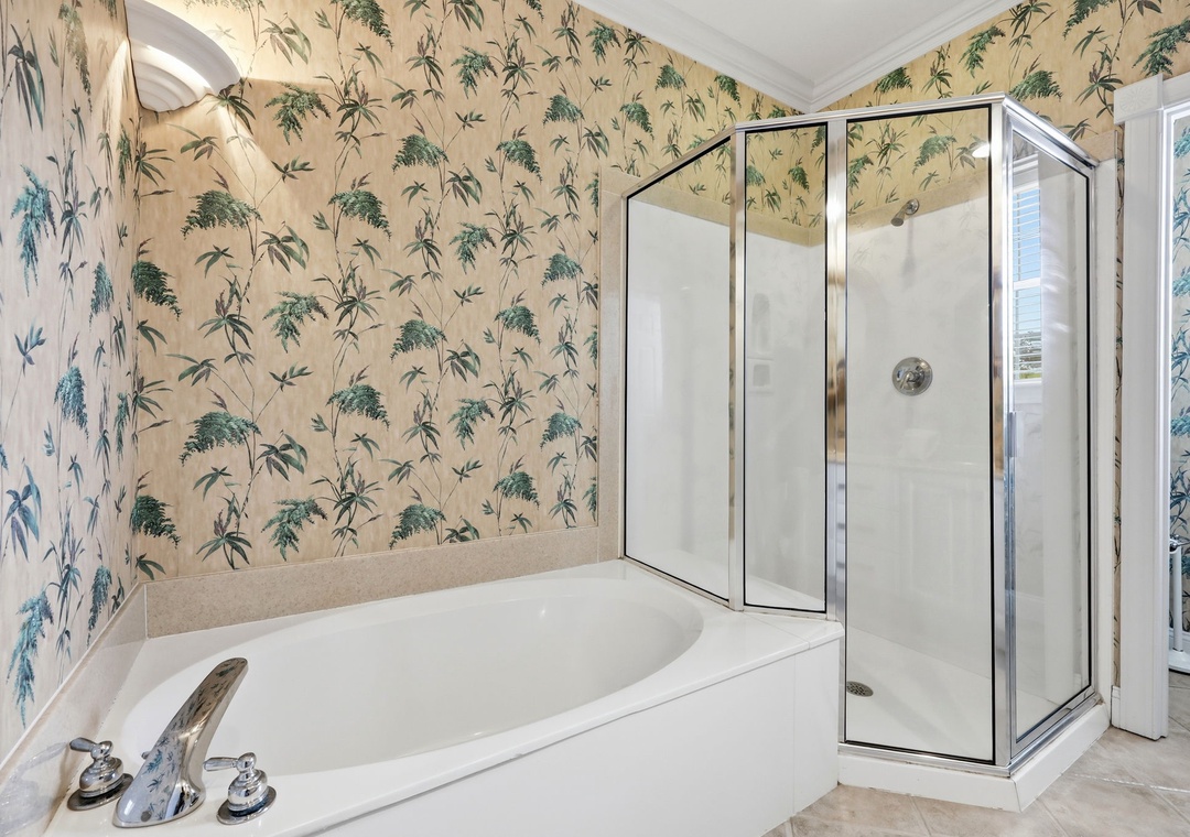 Spacious bathroom featuring a soaking tub and glass-enclosed shower, accented with charming botanical wallpaper to create your tranquil retreat.