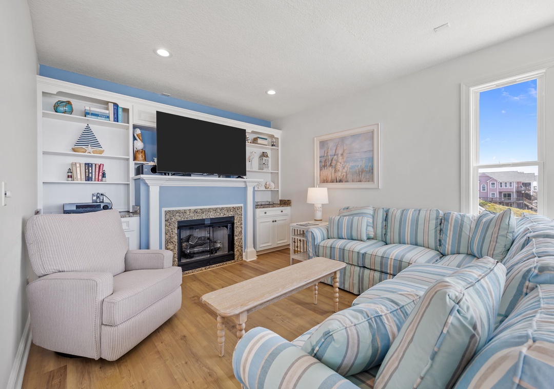 Sink into coastal comfort in your bright living room, where built-in shelves showcase local treasures and the fireplace invites cozy evenings.