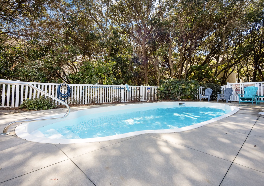 Dive into your private oasis! This sparkling pool beckons with crystal-clear water, surrounded by mature trees and comfortable seating for perfect relaxation.