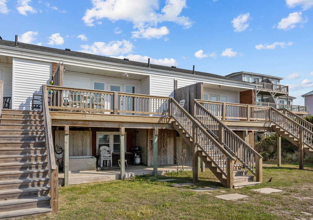 Coastal beach house with elevated wooden decks and stairs leading to comfortable accommodations in a peaceful seaside neighborhood.