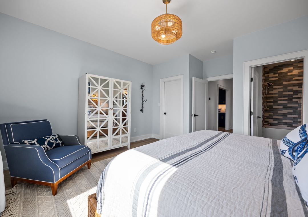 Unwind in your beautifully designed bedroom featuring soft linens, a cozy reading chair, and charming coastal touches that create the perfect retreat.