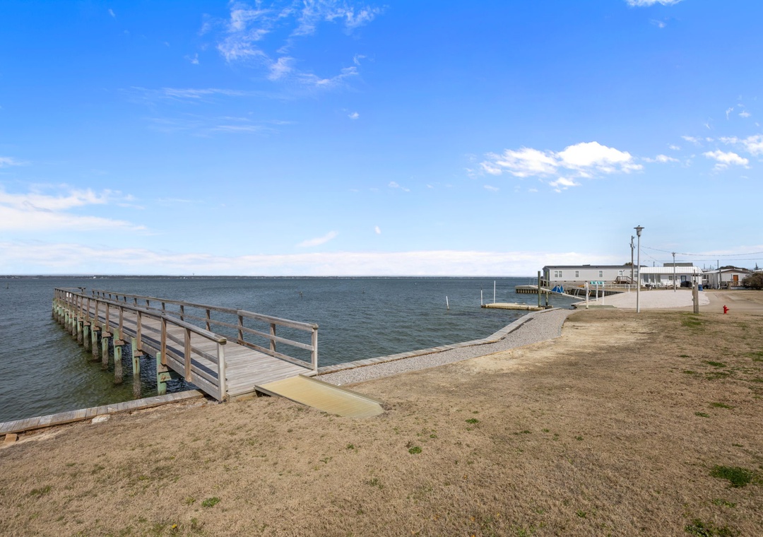 Peaceful waterfront location with wooden pier extending into calm waters, surrounded by coastal community buildings.