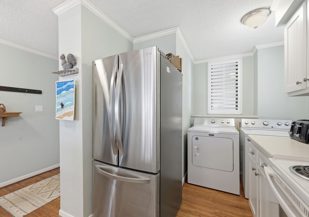 Bright and convenient kitchen corner featuring sleek stainless-steel fridge, in-unit washer and dryer, and modern stove—everything you need for a comfortable stay.
