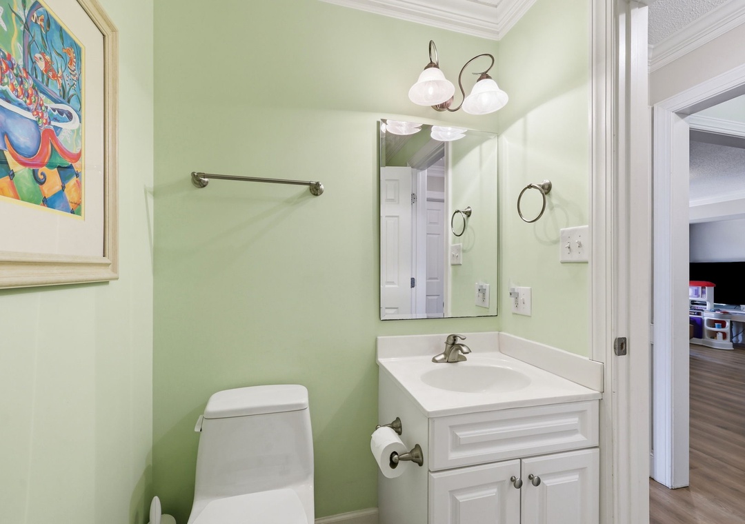 Freshen up in your cheerful bathroom, featuring soft green walls, a clean vanity, and playful artwork that adds charm to your daily routine.