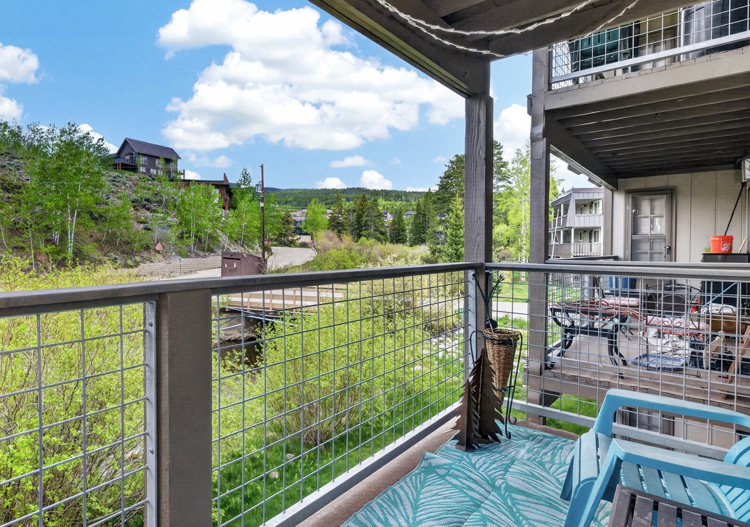 The property is nestled in a tranquil mountain setting, surrounded by lush greenery and distant hillsides, offering a peaceful retreat away from the bustle.
