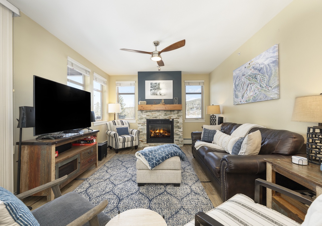 Relax in your cozy living room with a crackling fireplace, comfortable leather seating, and mountain views through large windows.
