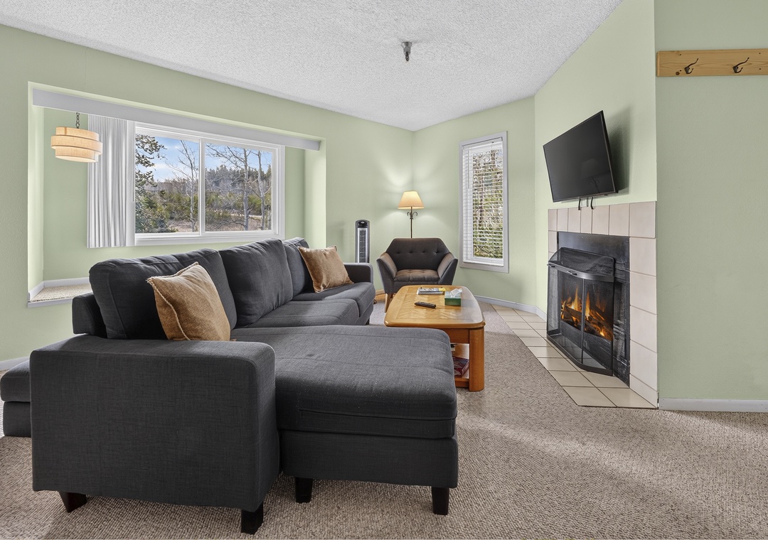 Unwind on the plush sofa by the cozy fireplace, or gaze out at peaceful wooded views framed by large windows—your perfect retreat after exploring nearby trails.