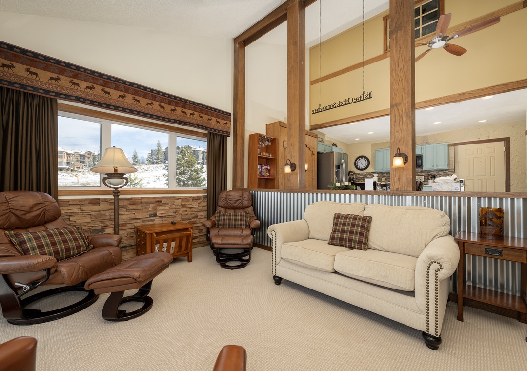 Unwind in your cozy mountain retreat at Mountainside Unit B-8 with rustic charm, leather seating, and stunning winter views through expansive windows.