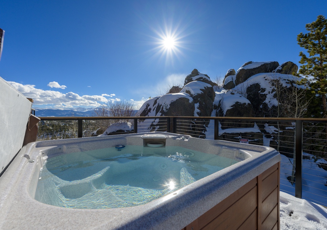 Soak in the bubbling hot tub while surrounded by snow-dusted boulders and endless mountain views under brilliant blue skies.