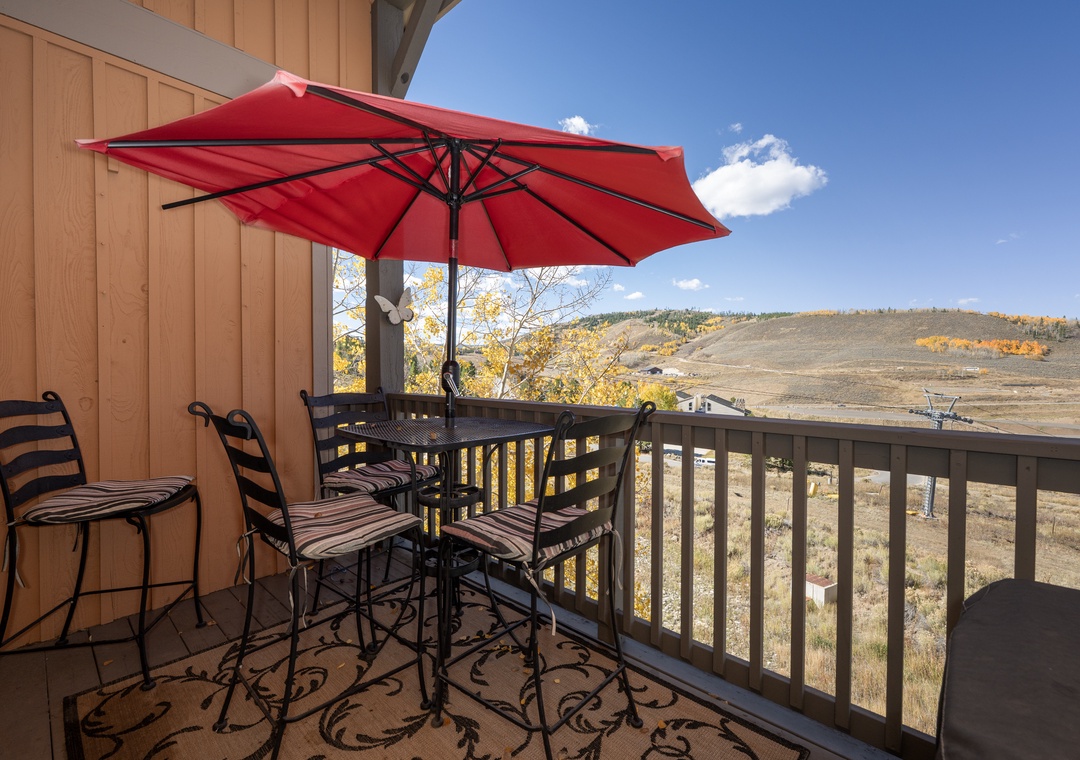 Your private balcony offers breathtaking mountain views with comfortable seating and shade for perfect outdoor dining moments at Kicking Horse Palomino 7-302.
