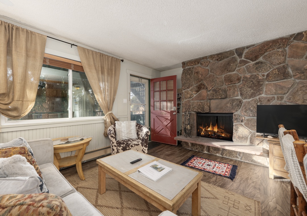 Cozy up by your crackling stone fireplace after mountain adventures. This rustic living room wraps you in warmth and charm.