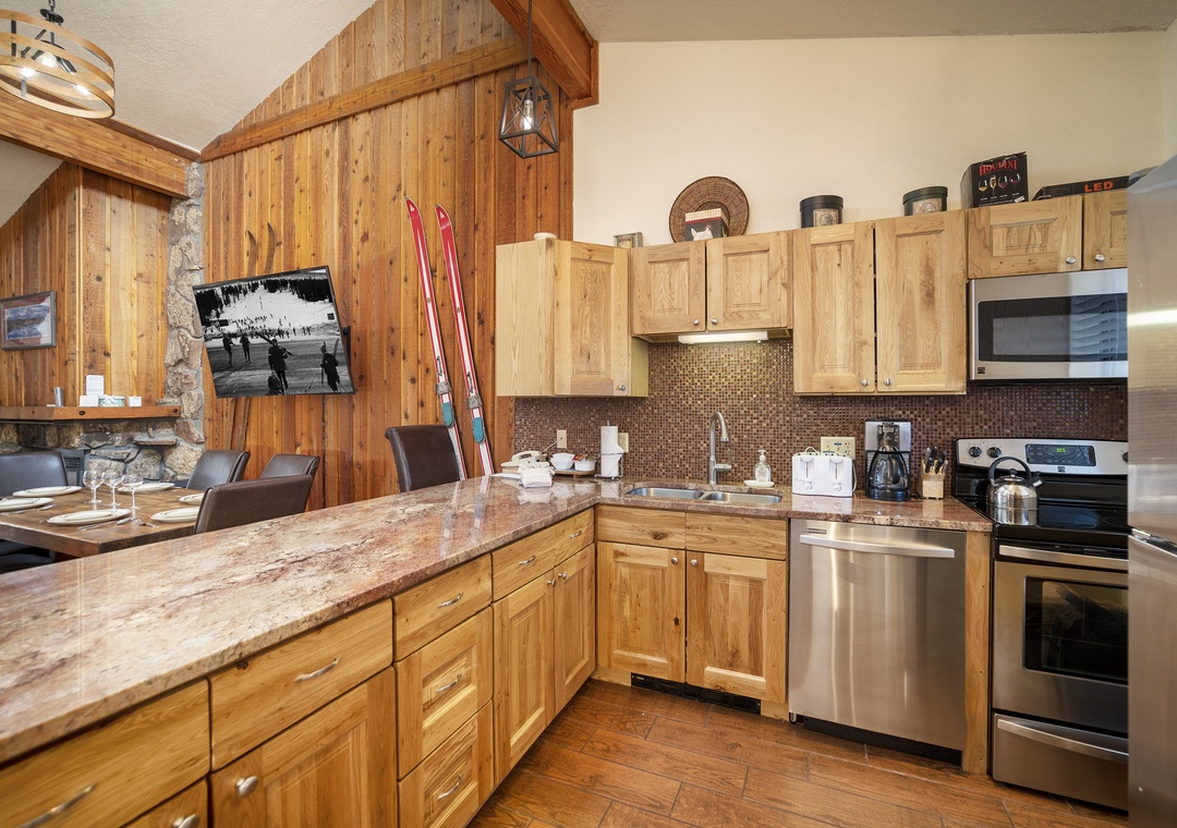 Your rustic alpine kitchen features granite counters, stainless appliances, and cozy wood accents perfect for preparing meals after skiing adventures.