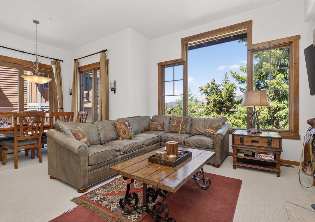 Unwind in your spacious living room with mountain views through large windows. Plush sectional seating and rustic wood accents create a warm, inviting atmosphere perfect for relaxing after your adventures.