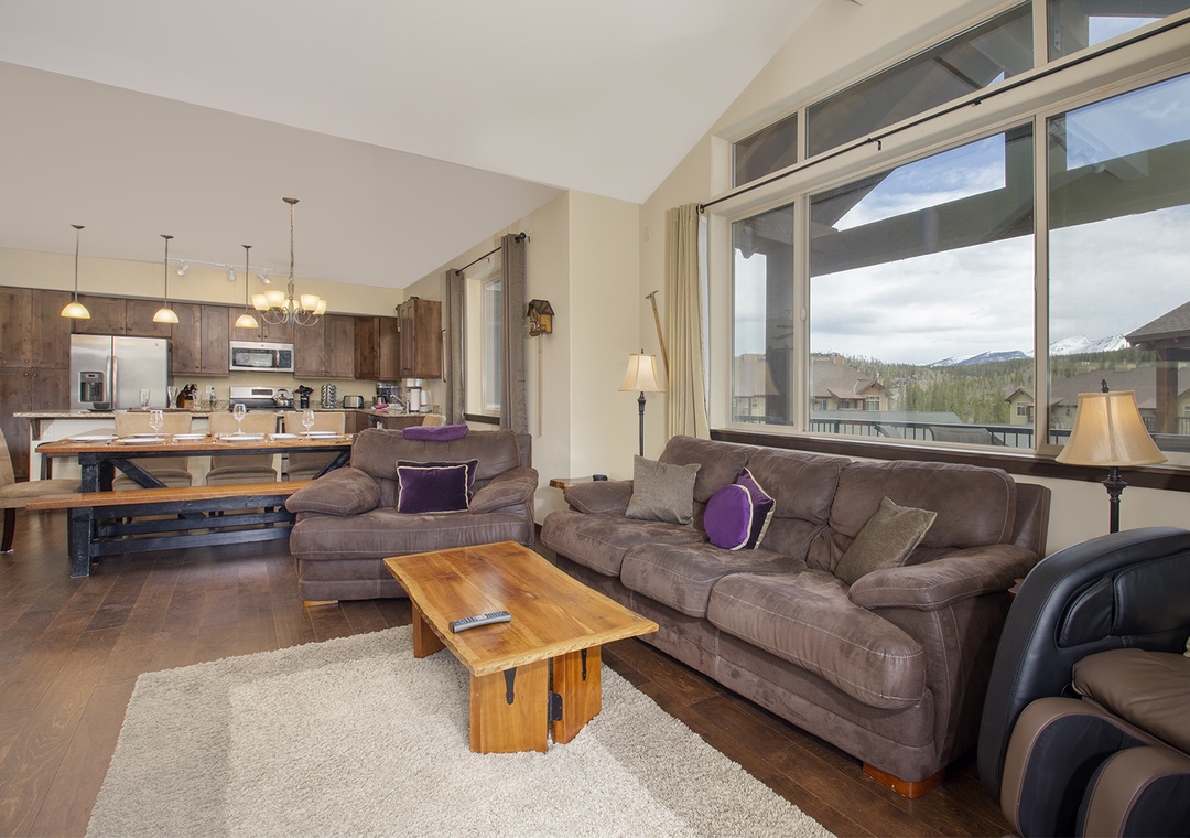 Relax in your spacious open-concept living area with mountain views through floor-to-ceiling windows while you unwind on the plush sectional sofa.