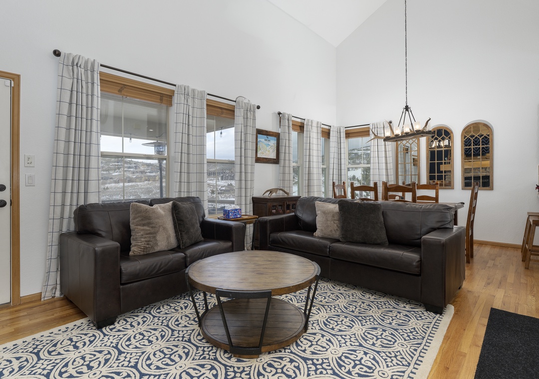 Sink into plush leather sofas in your open living space, where large windows frame mountain views and cozy details invite relaxation.