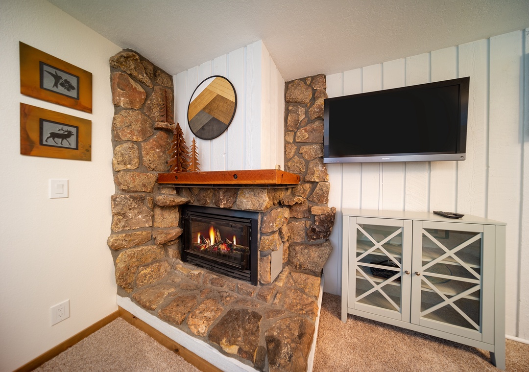 Cozy up by your stone fireplace with crackling flames while enjoying shows on the wall-mounted TV in this comfortable living space.