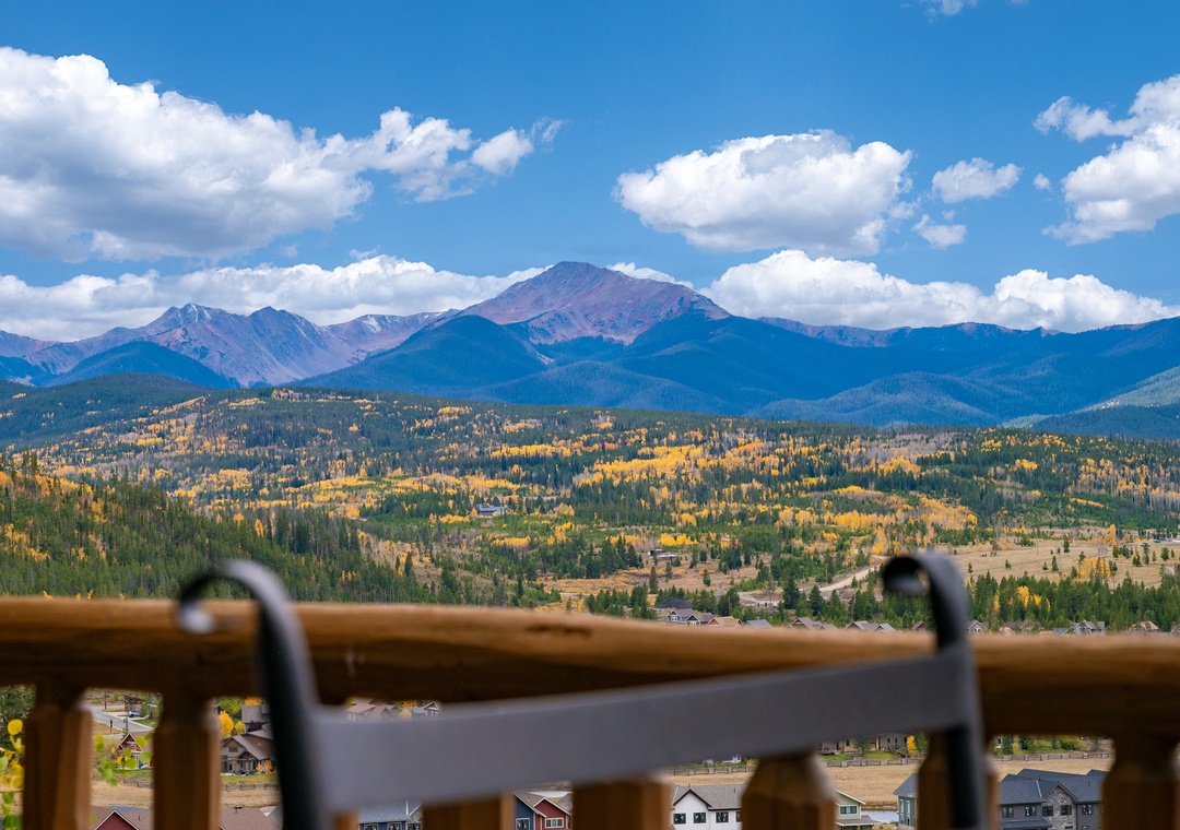 Spectacular mountain panorama showcases dramatic peaks and golden autumn foliage across the valley landscape.