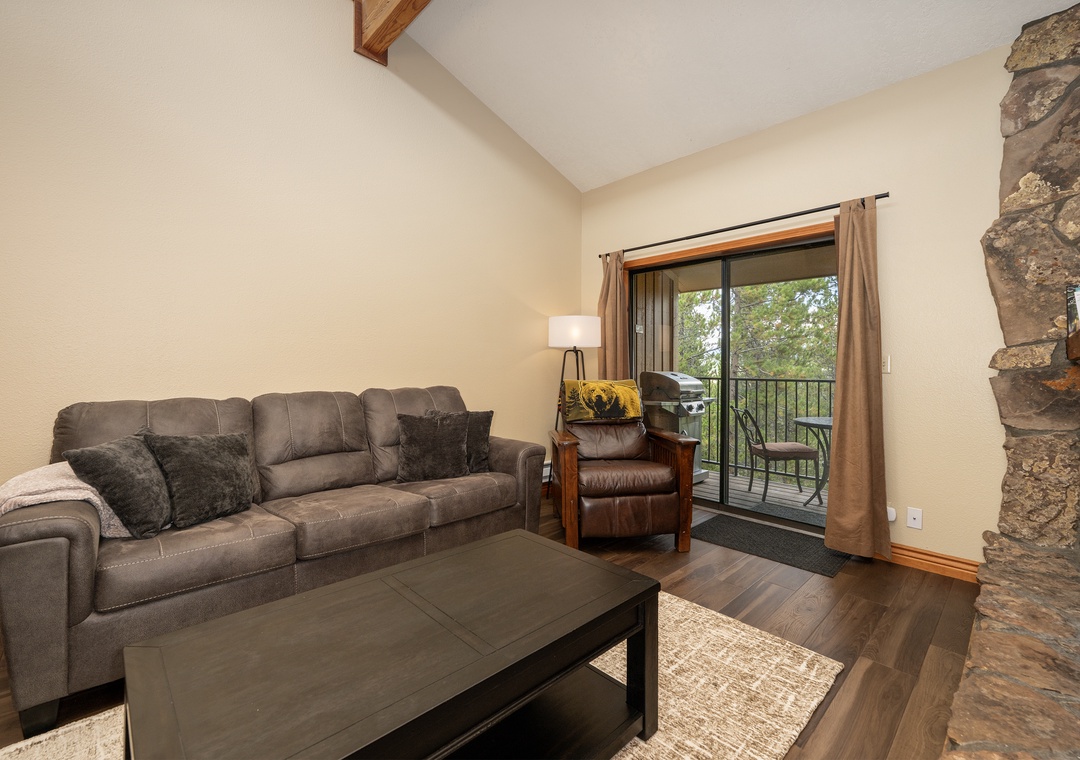 Unwind on the cozy sectional sofa with your morning coffee, enjoying peaceful tree views through the sliding glass doors to your private balcony.