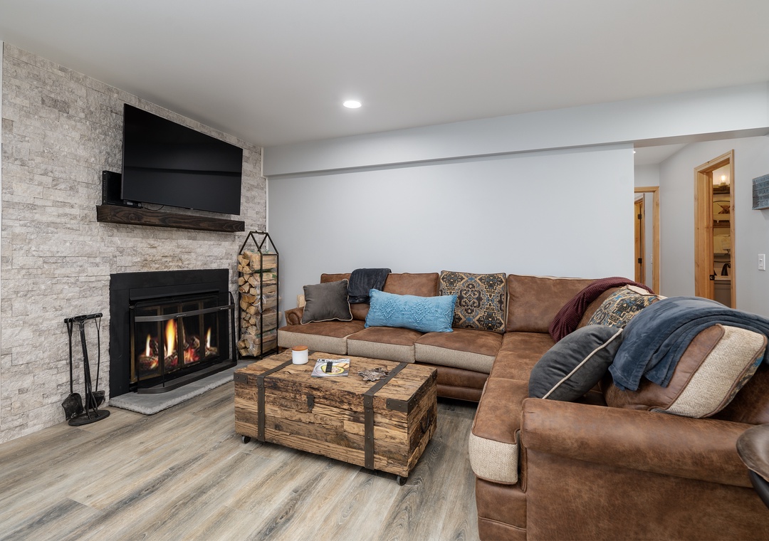 Unwind by the crackling fireplace in this cozy living space, where plush leather seating and warm lighting create your perfect retreat.