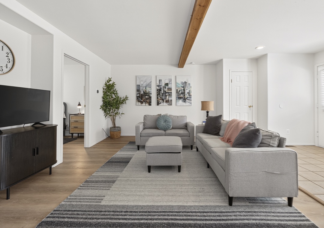 Sink into plush sofas and unwind in your bright, modern living space—high ceilings and warm wood beams create the perfect backdrop for relaxation after a day of exploring.