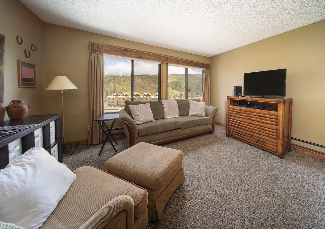 Relax in your spacious living room with comfortable seating and stunning mountain views framed by large windows.