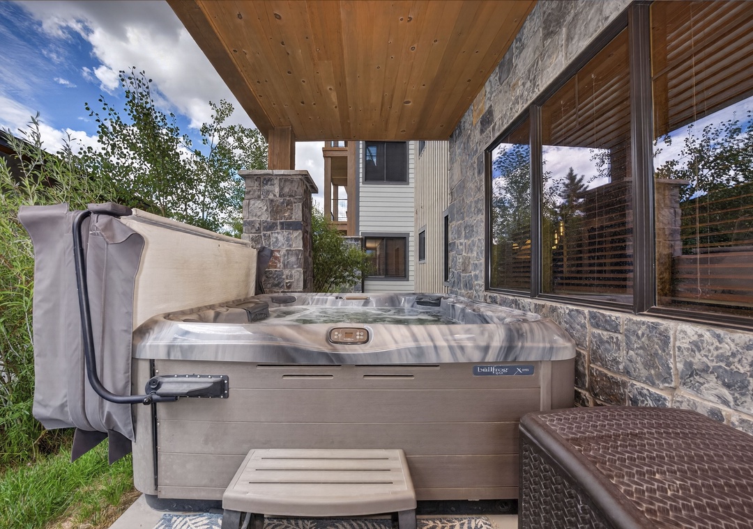 Soak under the open sky in your private hot tub, surrounded by natural stone and lush greenery, with modern mountain architecture as your backdrop.