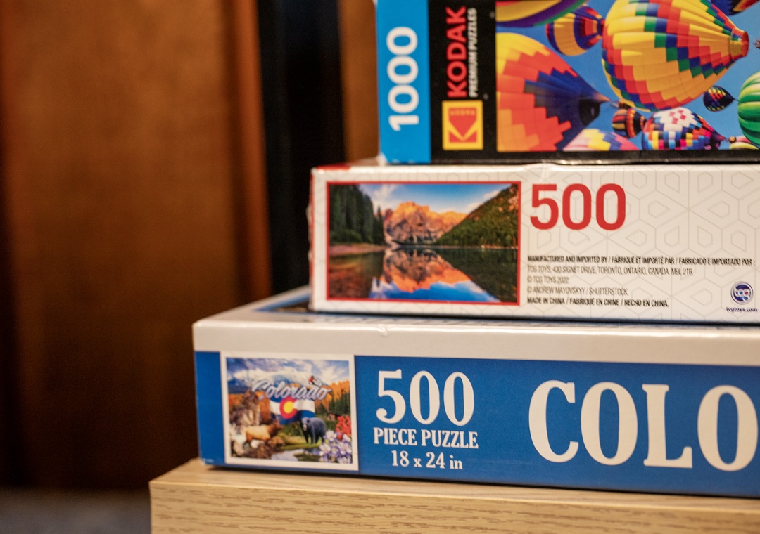Cozy up with puzzles for a perfect rainy day escape. Stack of games ready for your relaxing indoor adventure.