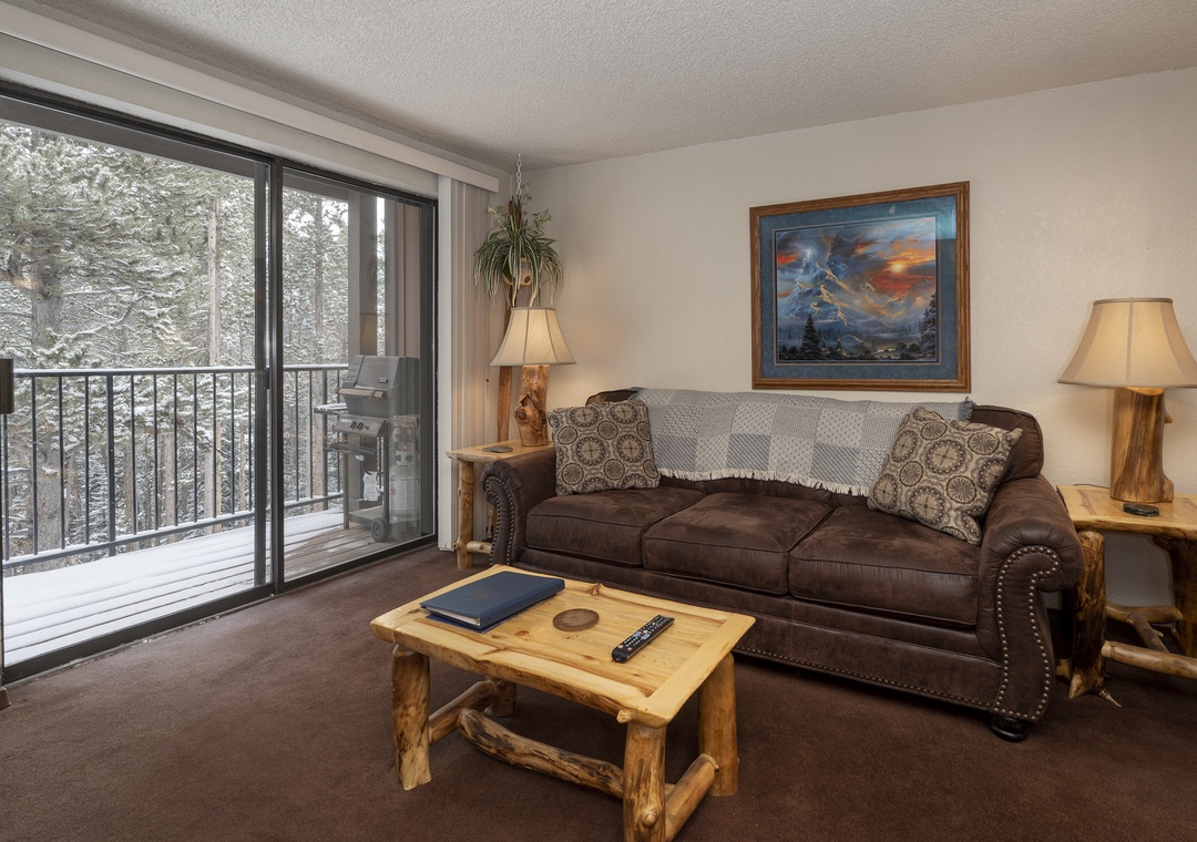 Cozy up on your leather sofa while admiring winter forest views through floor-to-ceiling windows on your private balcony.