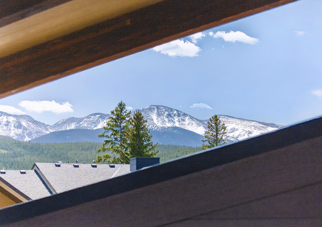 Spectacular mountain panorama frames snow-capped peaks and evergreen forests visible from this elevated vantage point.