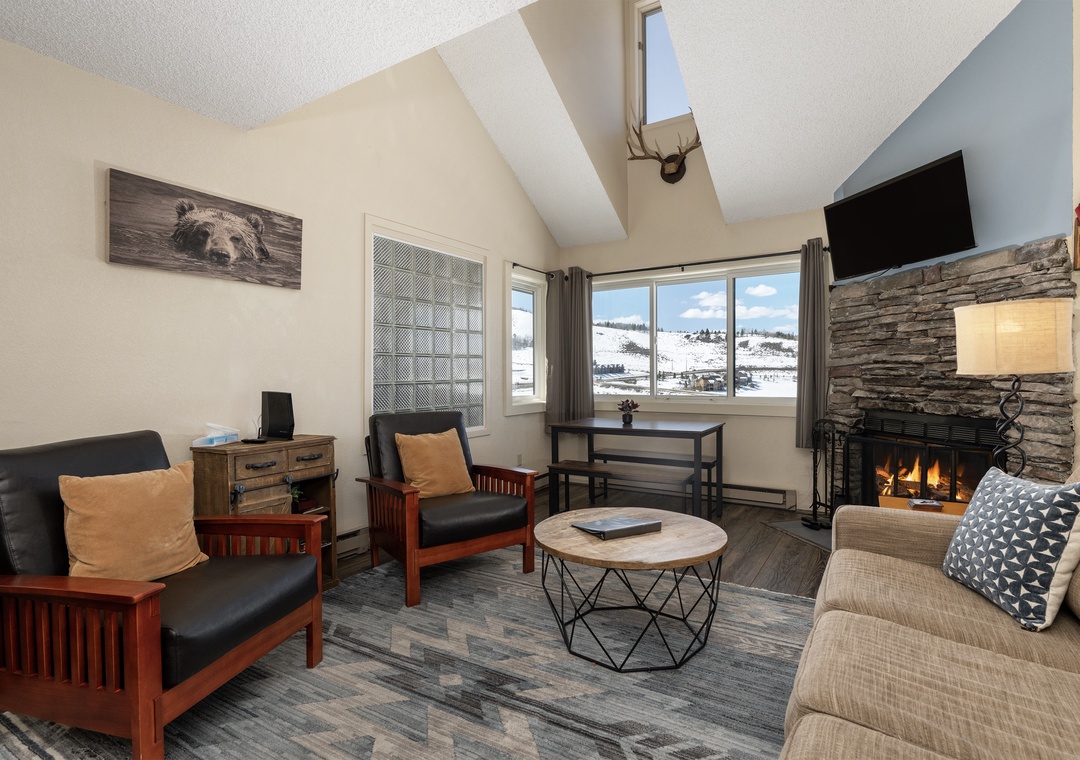 Cozy up by your stone fireplace at Summit Unit 1303 while gazing at snowy mountain views through expansive windows in this inviting alpine retreat.