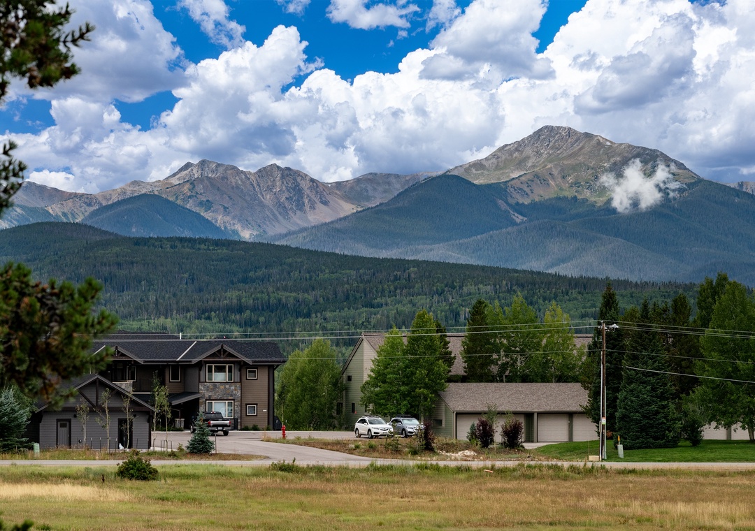 Mountain community nestled beneath dramatic peaks with residential neighborhoods surrounded by natural forest landscape.